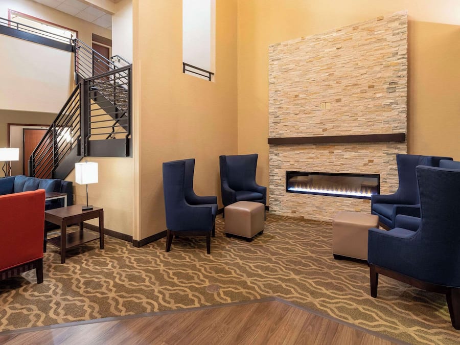A lobby with a fireplace, seating area, and a staircase.
