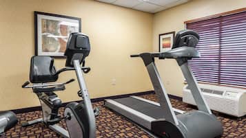 Ein Fitnessraum mit einem Crosstrainer, einem Laufband und einem stationären Fahrrad.