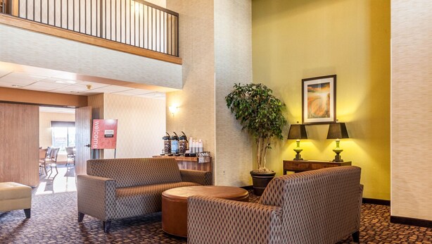 A lobby with seating, a reception desk, a plant, and a painting on the wall. - Quality Inn Clarksdale (Clarksdale)