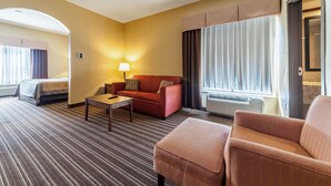 A hotel room with a bed, a sofa, a small table, and a window with curtains. - Quality Inn Clarksdale (Clarksdale)