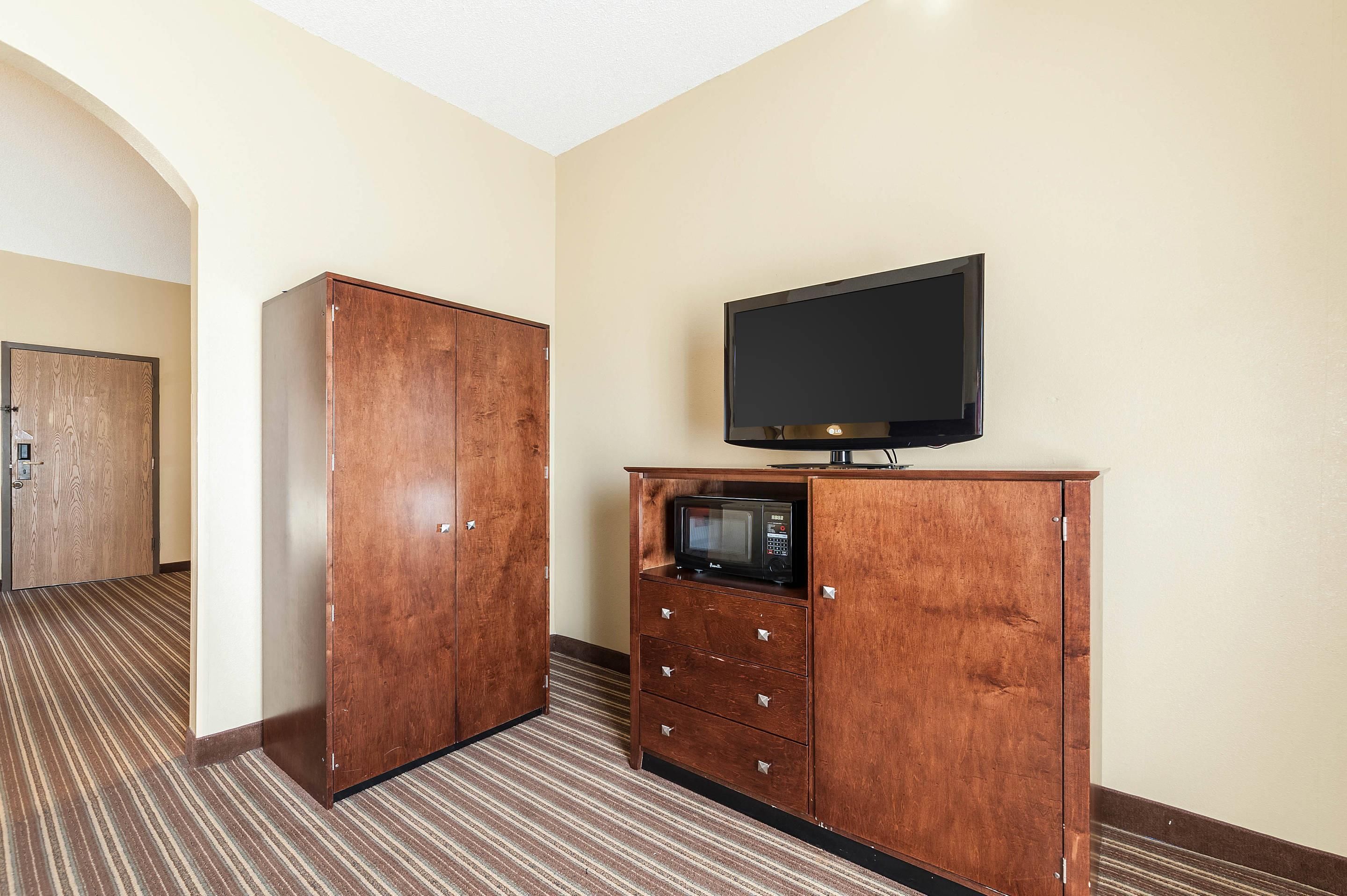 Ein Hotelzimmer mit Holzschrank, Flachbildfernseher und Mikrowelle.