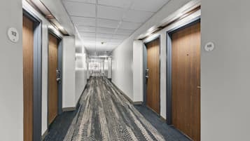 A hallway with doors numbered 112 and 113, carpeted floor, and a ceiling with recessed lighting.