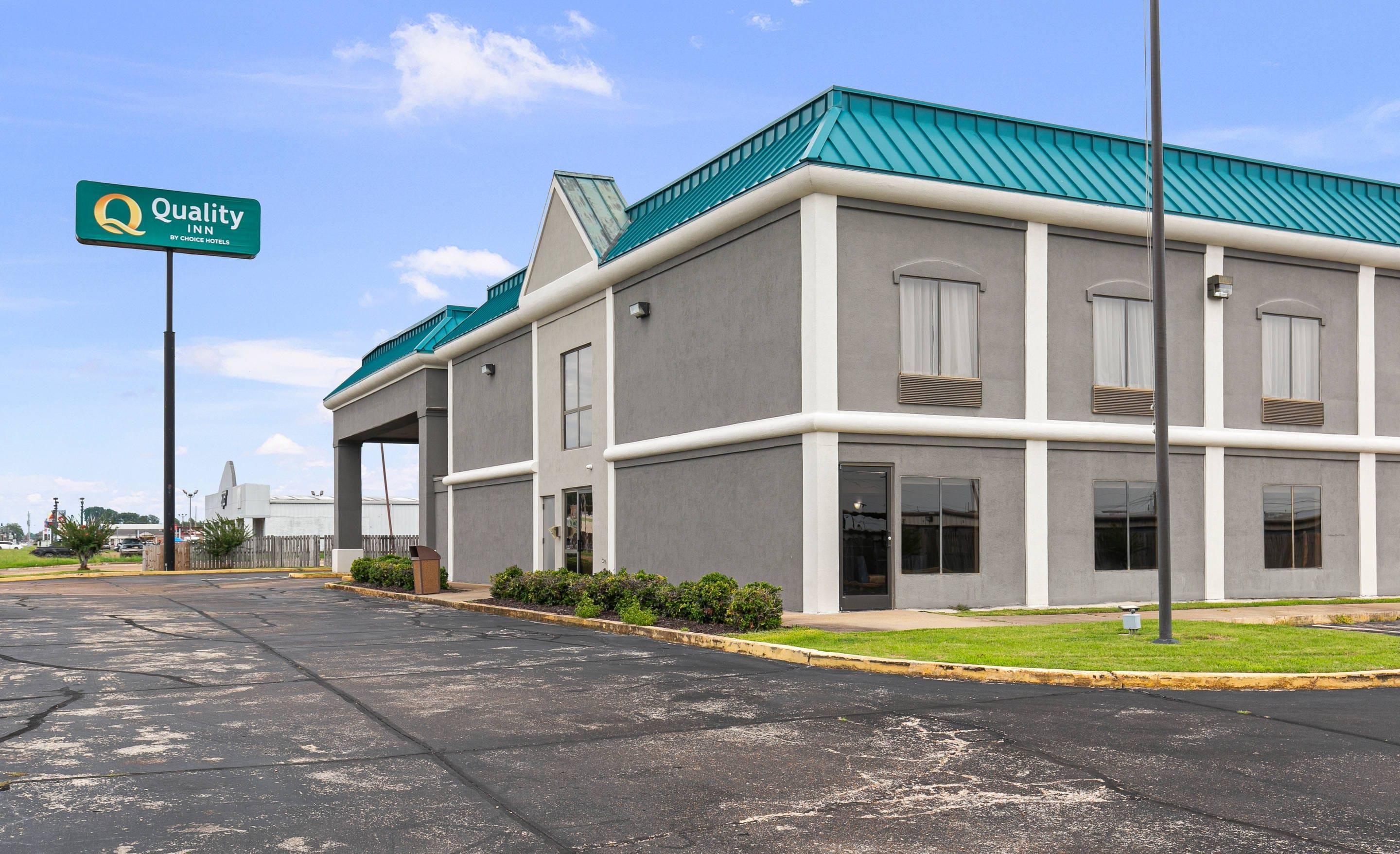 Un bâtiment d’hôtel doté d’un toit végétalisé, de nombreuses fenêtres et d’une enseigne indiquant qu’il s’agit d’un hôtel Quality Inn, membre du groupe Choice Hotels.