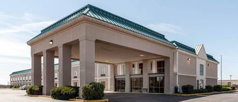 A hotel with a covered entrance, large columns, and a green roof.