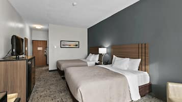 A hotel room with a bed, bedside tables, a desk, and a television.
