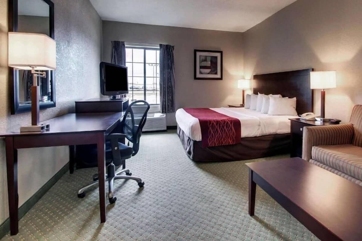 A hotel room with a bed, desk, chair, and a television.