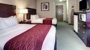 A hotel room with two beds, a TV, a desk, and a door leading to a hallway. - Columbia Inn & Suites (Columbia)