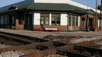 Andén de estación de tren con un cartel que dice 'CORINTH' y varias vías.