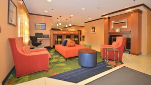 A lobby with a reception desk, seating area with chairs and a sofa, a small table, and a fireplace. - Fairfield Inn & Suites by Marriott - Jefferson City (Jefferson City)