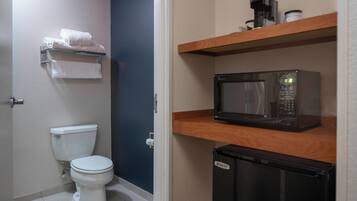 Un baño pequeño con inodoro, microondas y refrigerador.