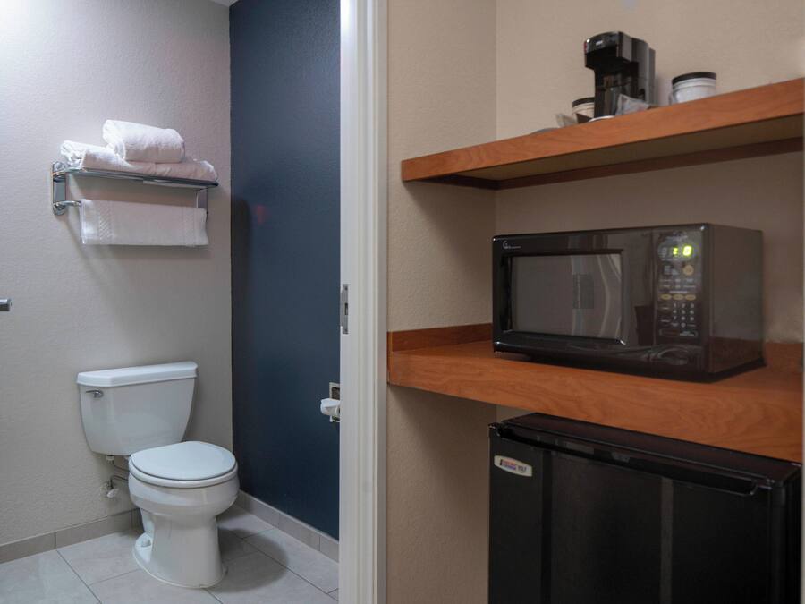 Un baño pequeño con inodoro, microondas y refrigerador.