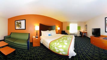 A hotel room with a bed, a green sofa, a desk, a television, and a small table.