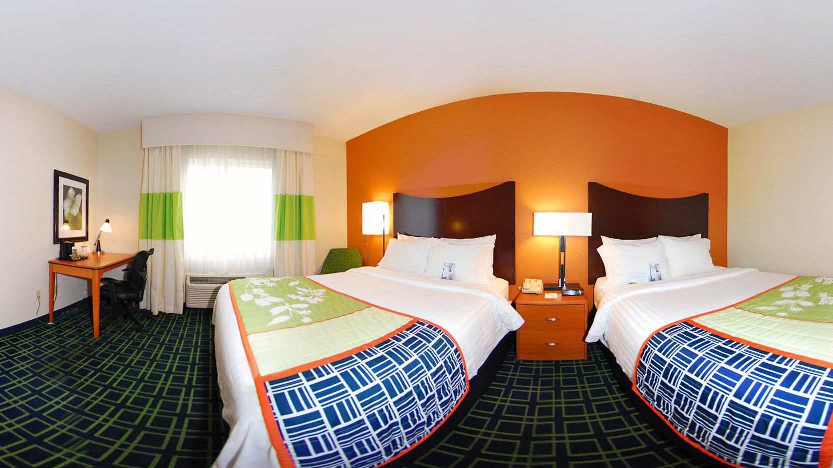 A hotel room with two beds, a desk, and a chair.