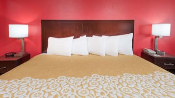 Habitación de hotel con una cama grande, paredes rojas y dos mesitas de noche con lámparas.