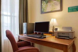 Habitación de hotel con escritorio, computadora, impresora y una silla.