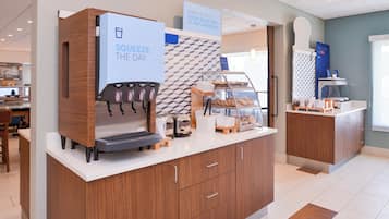 A coffee station with a branded coffee machine and a sign that reads 'SQUEEZE THE DAY'.