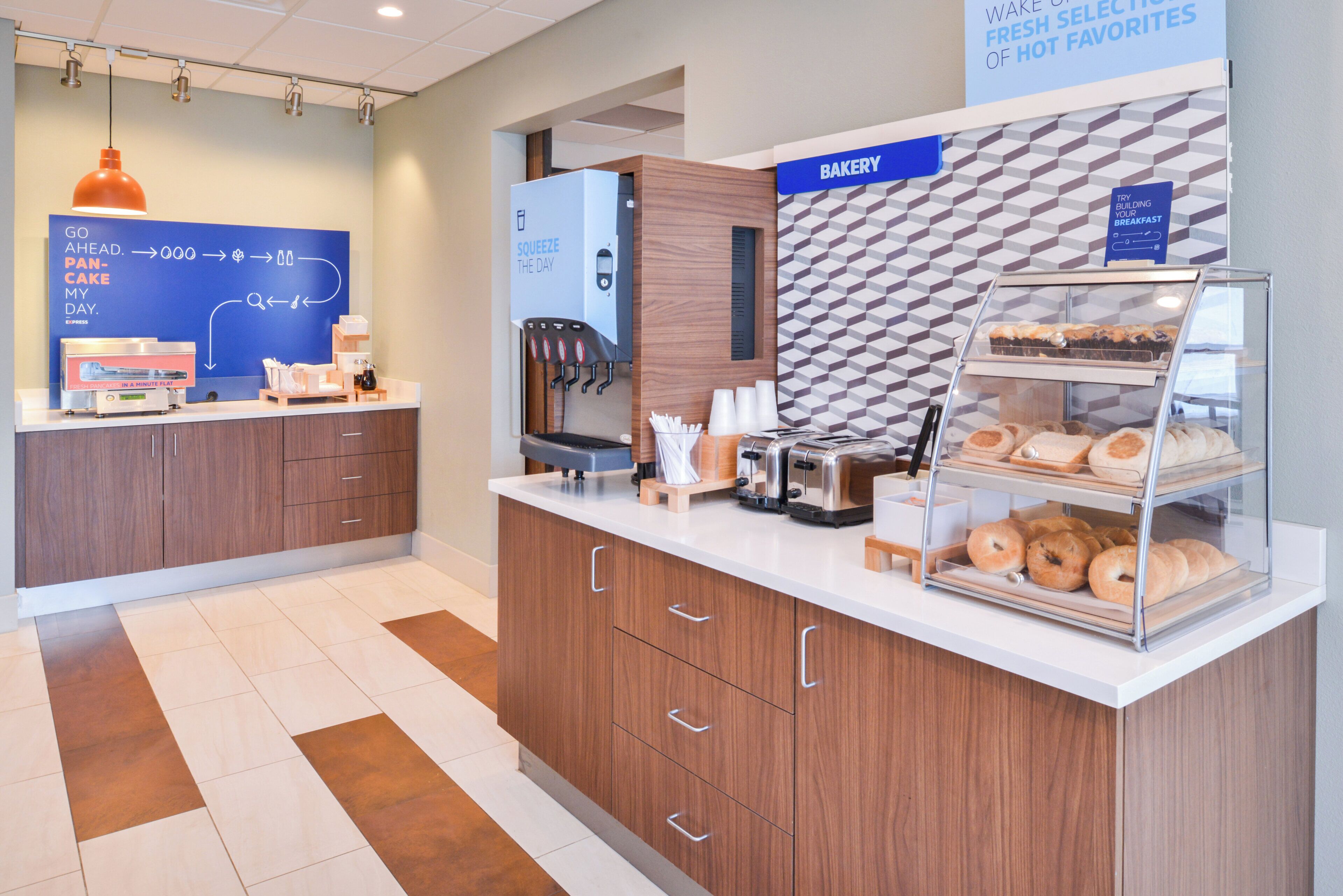 A modern breakfast area with a coffee machine, a pastry display, and a sign indicating a bakery.