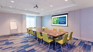 A conference room with a large table, yellow chairs, a whiteboard, and a screen displaying the Holiday Inn Express logo. - Holiday Inn Express & Suites Omaha - 120th and Maple by IHG (Omaha)