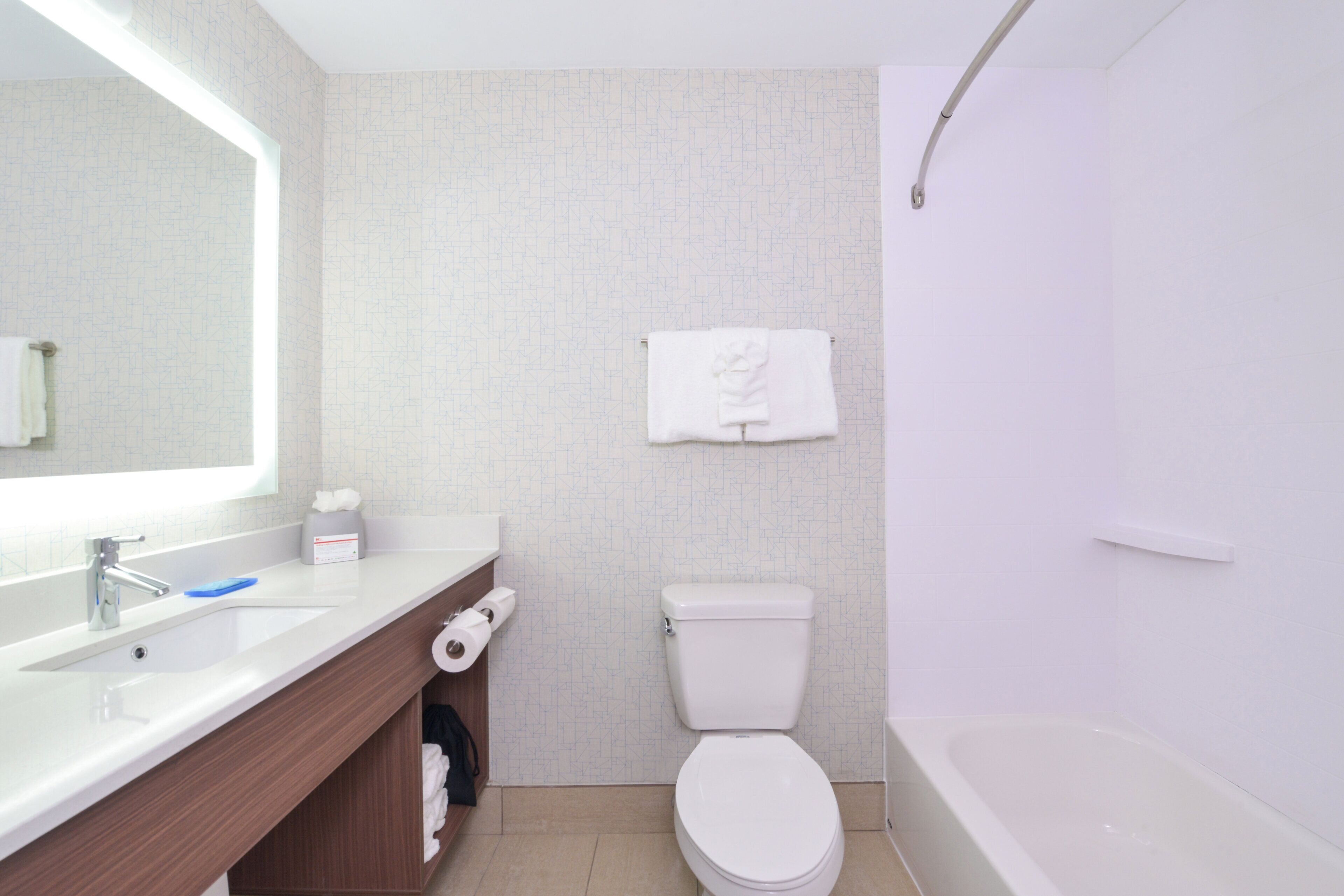Ein modernes Badezimmer mit Toilette, Waschbecken mit Spiegel und einer Badewanne.