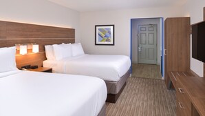 A hotel room with two beds, a wooden headboard, a framed artwork, a door, and a TV. - Holiday Inn Express & Suites Omaha - 120th and Maple by IHG (Omaha)
