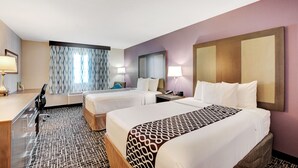 A hotel room with two beds, a desk, and a large mirror on the wall.