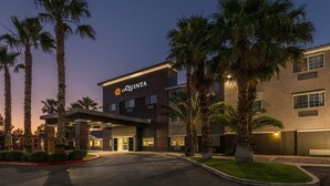 A hotel with a modern design, featuring palm trees and a well-lit entrance.