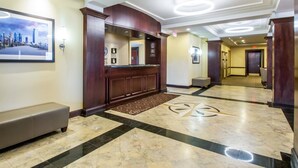 A hotel lobby with a reception desk, a bench, and a patterned floor. - Comfort Suites at Woodbridge (Avenel)