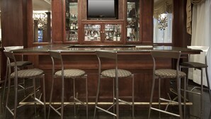 A bar area with a flat-screen TV, wooden cabinets, and bar stools. - Comfort Suites at Woodbridge (Avenel)