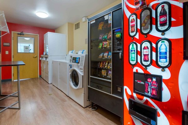 A laundry area with a washing machine and dryer, a vending machine with snacks, and a Coca-Cola refrigerator.