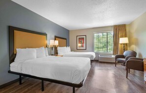 A hotel room with two beds, a desk, a chair, a window with curtains, and a wall-mounted air conditioner. - Extended Stay America Suites Hanover Parsippany (Whippany)
