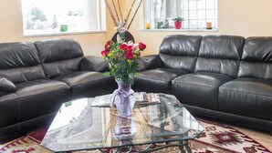 Una sala de estar con una mesa de centro de vidrio, un sofá de cuero negro y un florero con flores.