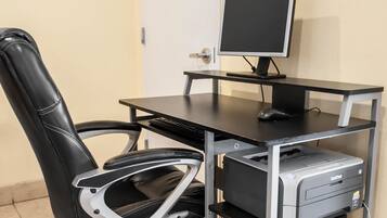 Ein schwarzer Bürostuhl mit hoher Rückenlehne, ein schwarzer Schreibtisch mit Monitor, Tastatur und Maus, sowie ein Brother-Drucker auf einem Metallständer.