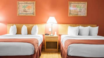 A hotel room with two beds, a nightstand with a lamp, and two framed pictures on the wall.