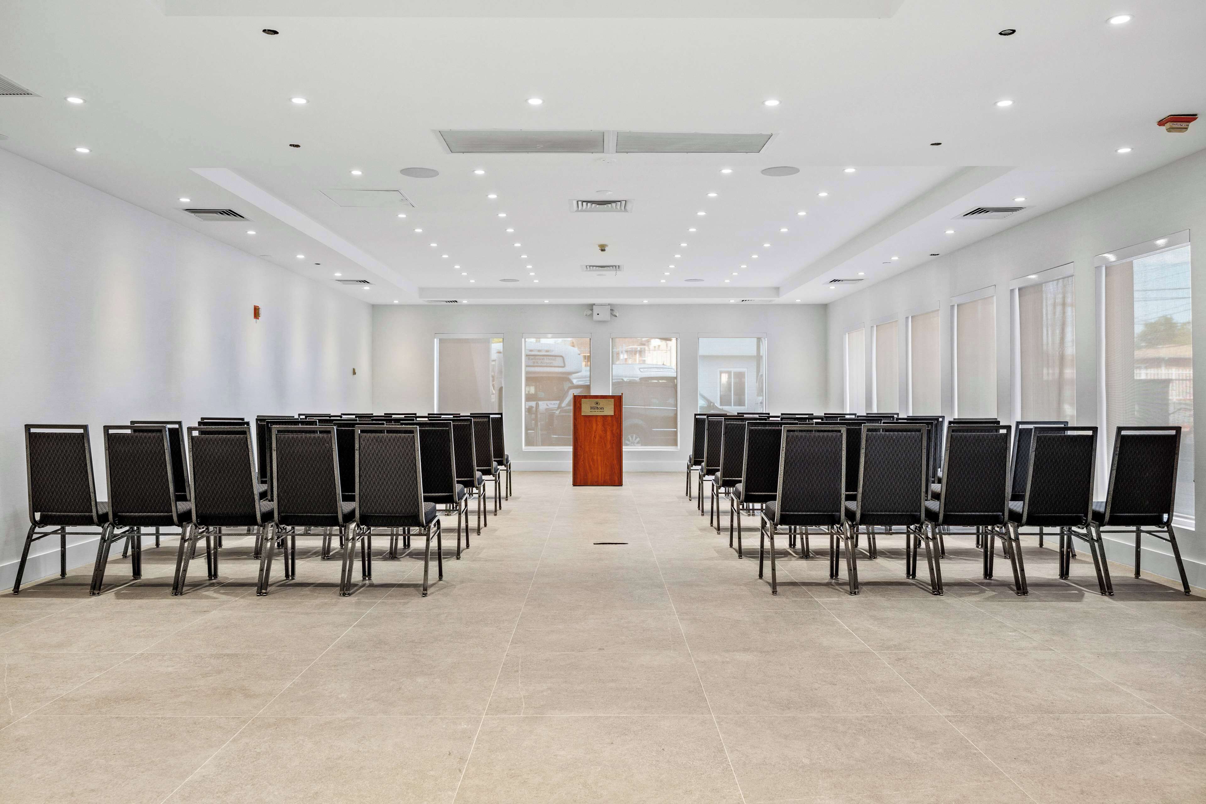 A conference room with rows of chairs, a podium, and large windows.
