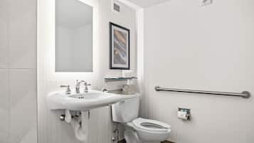 A modern bathroom with a white sink, toilet, and a handrail.