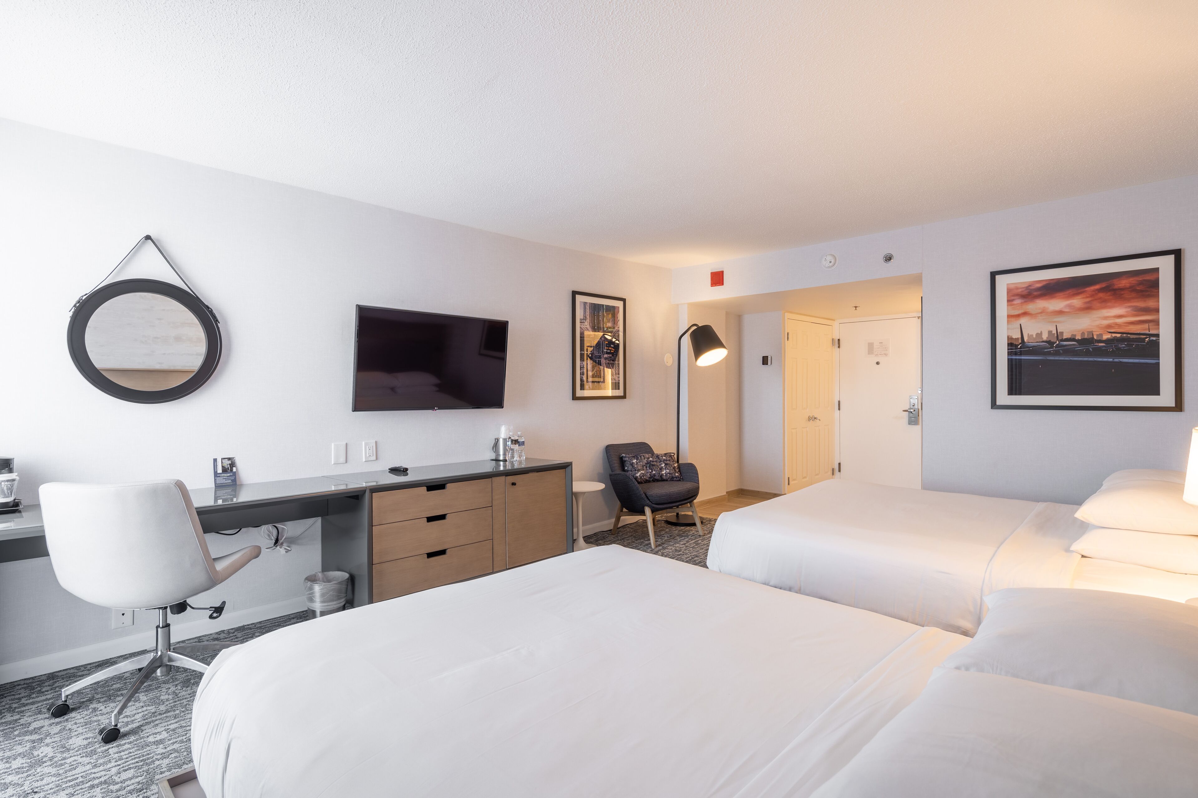 Ein Hotelzimmer mit Bett, Schreibtisch, Stuhl und Fernseher.