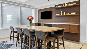 Eine moderne Küche mit Holztisch, Barhocker, einem Flachbildfernseher und eingebauten Regalen mit Dekorationsobjekten.