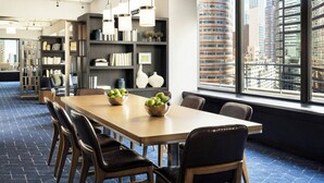 Une salle de conférence moderne, dotée d’une longue table, de chaises et d’étagères.