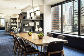 A modern conference room with a long table, chairs, and bookshelves.