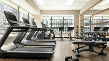Un gimnasio con cintas de correr, elípticas y pesas libres.
