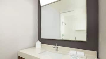 A modern bathroom with a large mirror, a sink, and a towel rack.