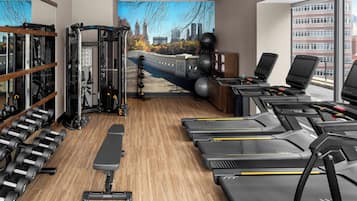 Un gimnasio con cintas de correr, mancuernas y una máquina de pesas.