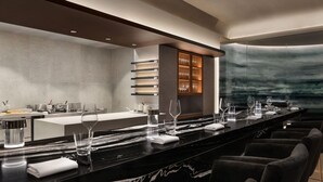 Un área de bar moderna con una barra larga, taburetes y un soporte para copas de vino.