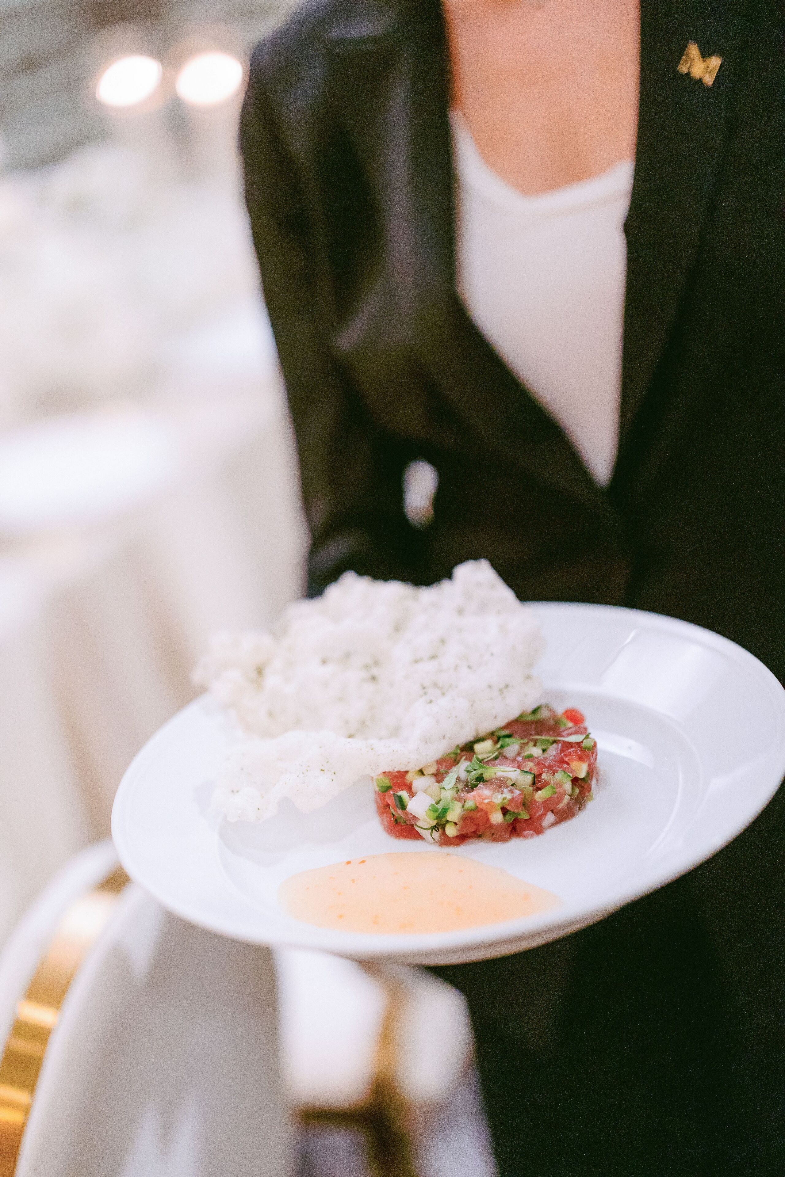 A person holding a plate with white rice and a meat dish, possibly steak tartare, with a side of sauce.