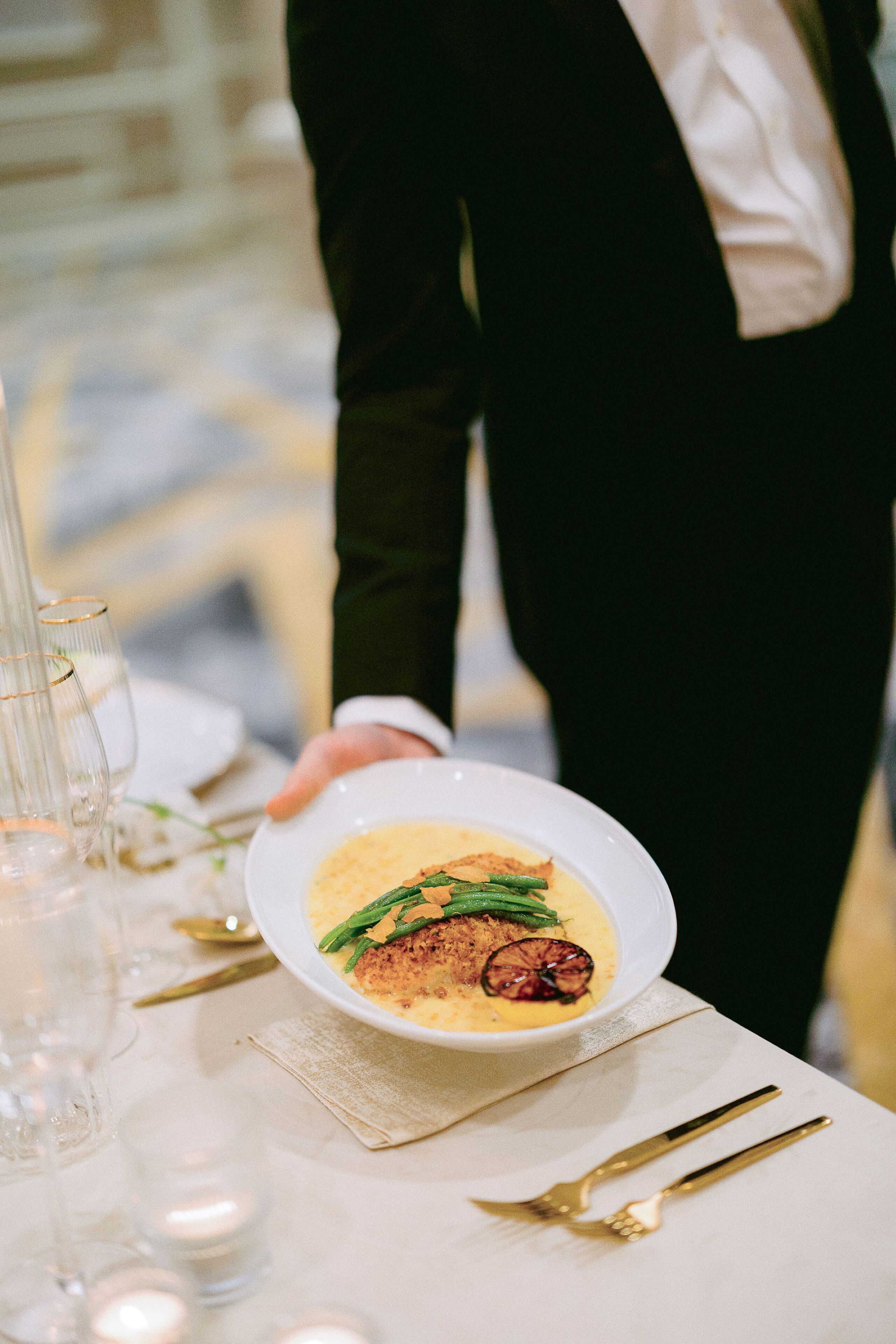A white table with a bowl of food, a glass, and a fork.