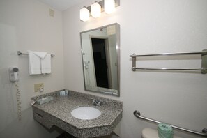 A bathroom with a granite sink, a mirror, a towel rack, a hand dryer, and a grab bar.