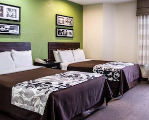 A hotel room with two beds, a green wall, and framed pictures.
