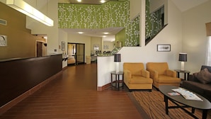 A hotel lobby with a reception desk, a staircase, and seating areas.