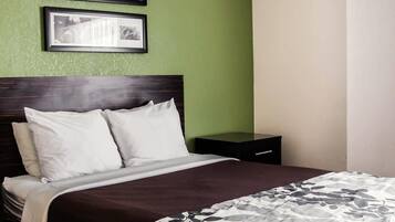 A neatly made bed with white linens and a floral-patterned blanket, a dark wooden headboard, and two framed pictures on the wall.