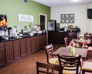 A dining area with a buffet setup, a refrigerator, and a coffee station.